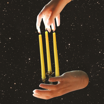 two hands hold up a candelabra with candles on it