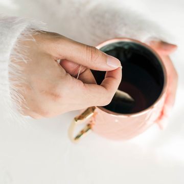woman with fuzzy sweater steeping tea in copper mug