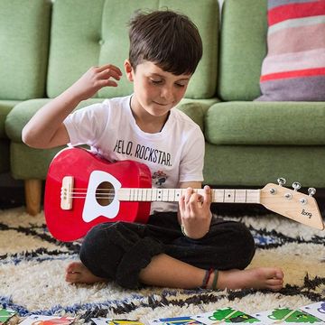 boy playing red guitar on carpet