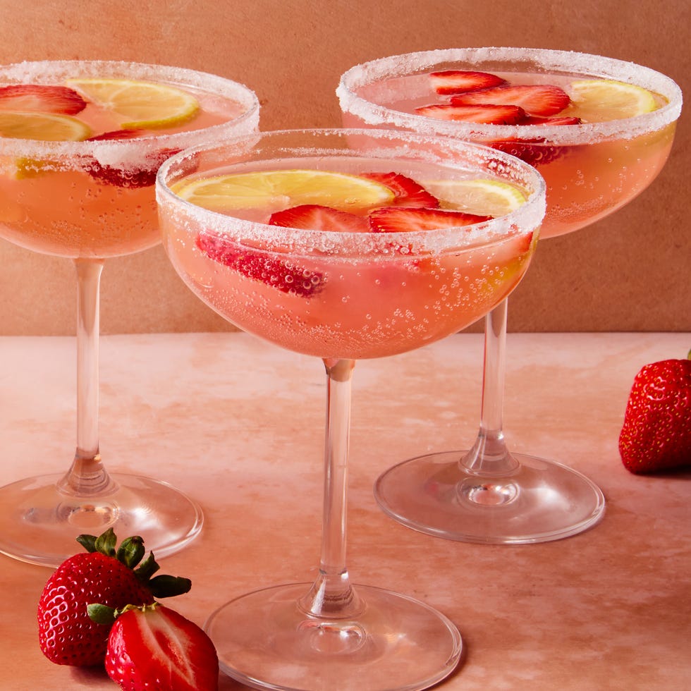 pink cocktail with sliced strawberries and lemon