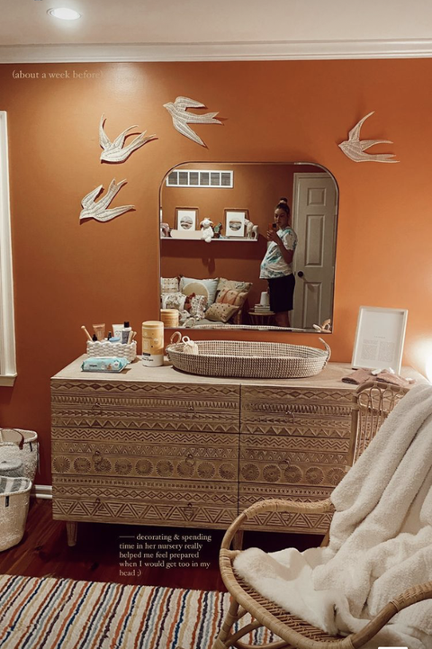 burnt orange wall with aztec dresser, basket, mirror, doves on wall