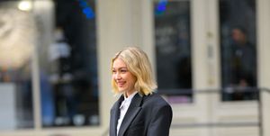 gigi hadid on the set of a maybelline photo shoot in new york wearing a cropped black suit jacket and wide leg suit trousers