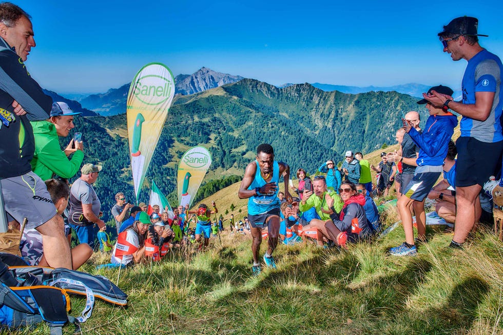 a runner races uphill amidst a cheering crowd during a mountain running event