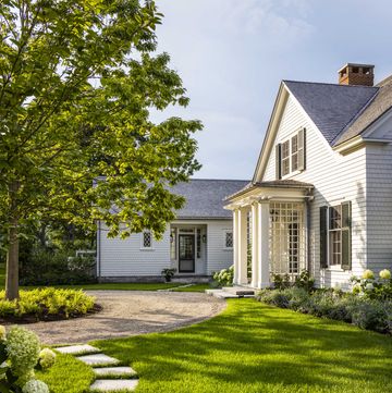 a white cottage style home with a green lawn