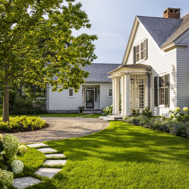 a white cottage style home with a green lawn
