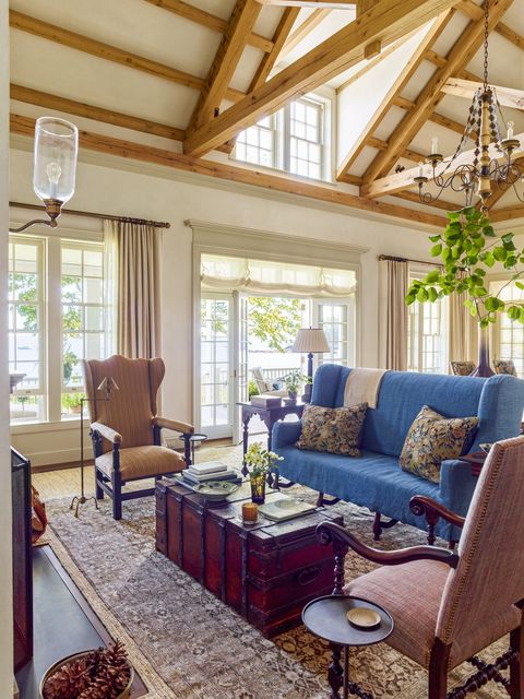 in the living room an antique needlepoint sofa is slipcovered in a cool ocean blue linen