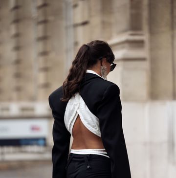 a woman wearing an open back black and white blazer and trousers on the street during paris fashion week spring summer 2023