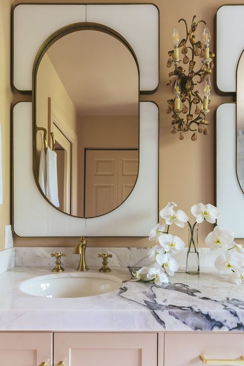 bathroom with oval mirrors and intricate gold sconce with faux candles