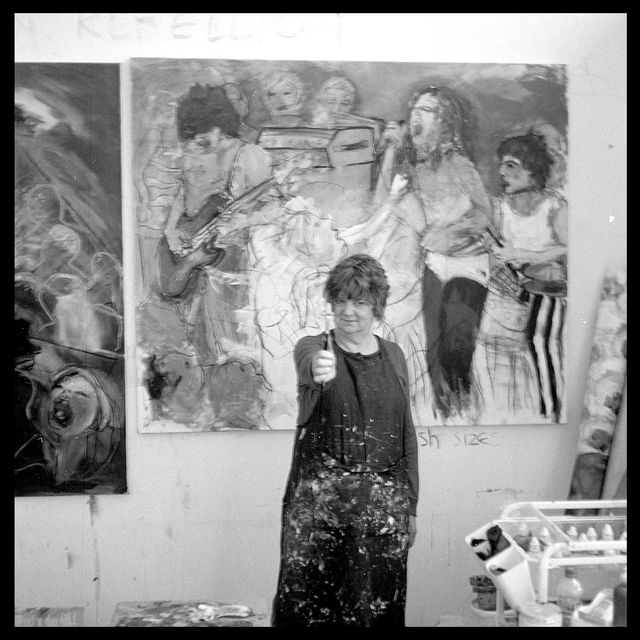 gina birch stands in front of a painting in progress