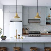 gray and white kitchen with brass pendants