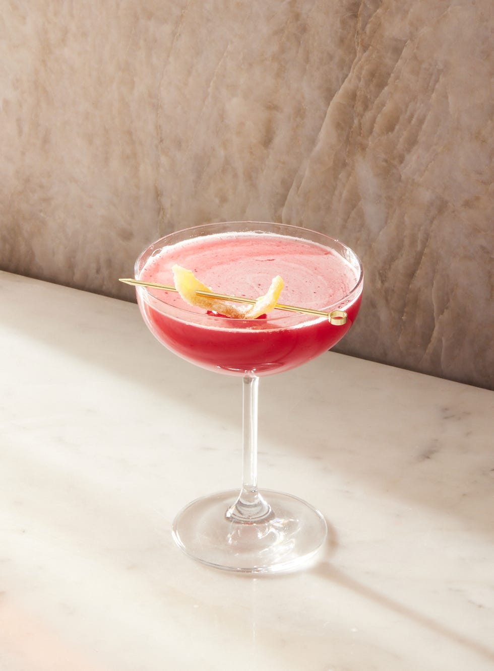 pink ginger cranberry whiskey sours in coupe glasses garnished with candied ginger