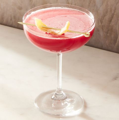 pink ginger cranberry whiskey sours in coupe glasses garnished with candied ginger