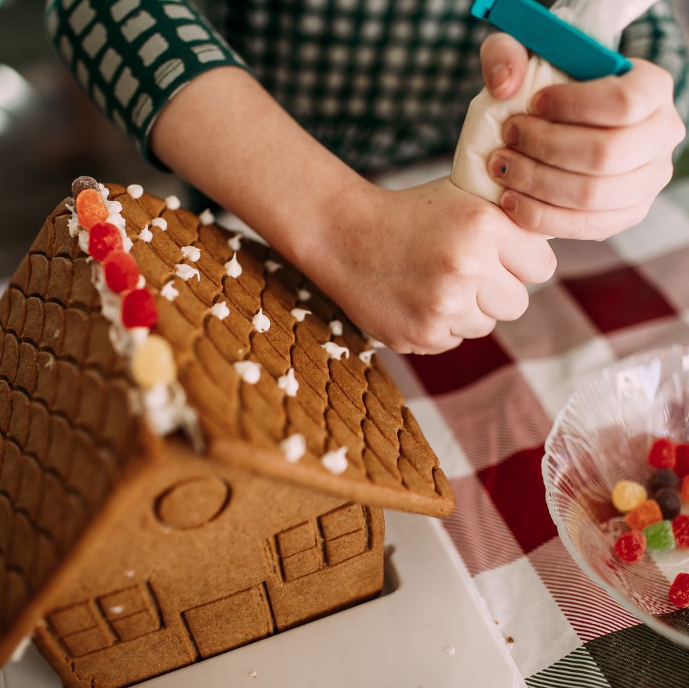 a person cutting a gingerbread house