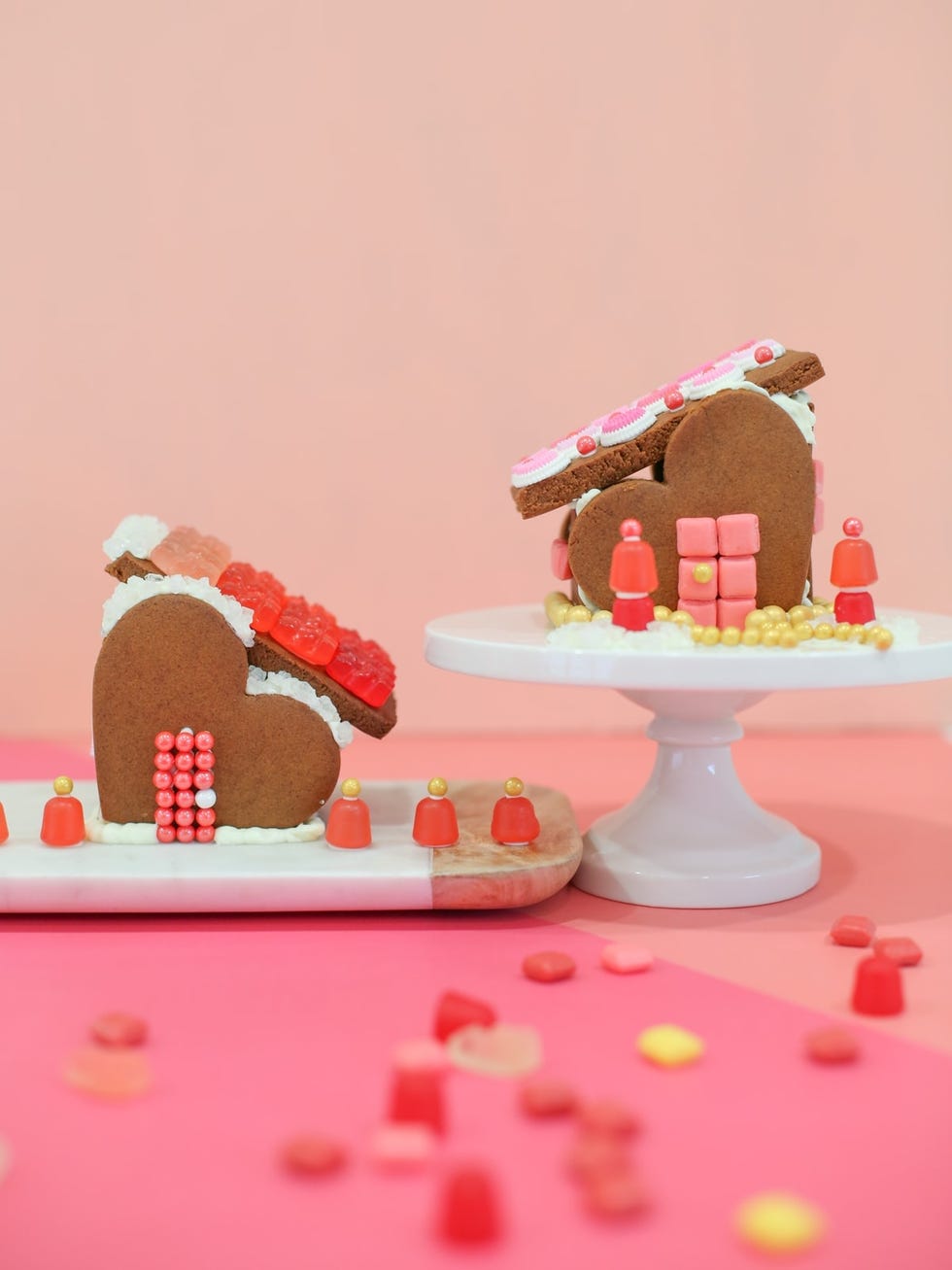 two heartshaped valentines day gingerbread houses decorated in red and pink candy