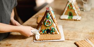 kid putting icing on gingerbread house