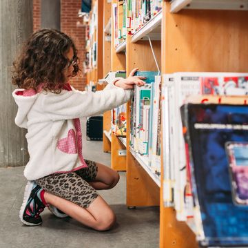 girl choosing books from the shelves of the public library