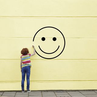girl drawing smiley face on to a wall