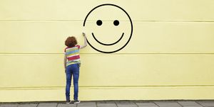 girl drawing smiley face on to a wall