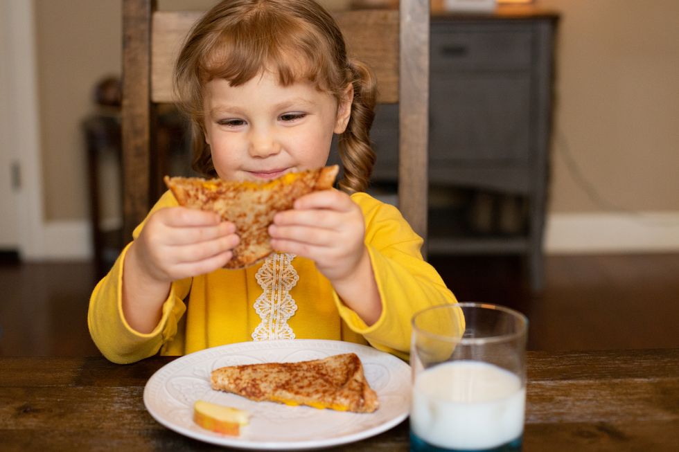 una niña se come un sandwich con queso