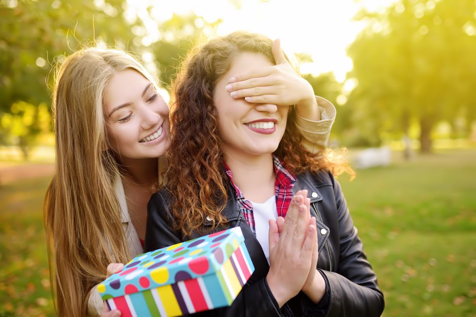 girl giving surprise birthday gift to friend