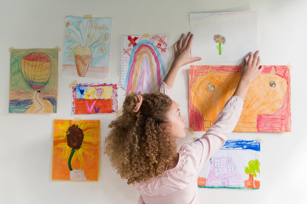 girl hanging artwork on wall