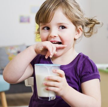 girl holding glass of milk at home