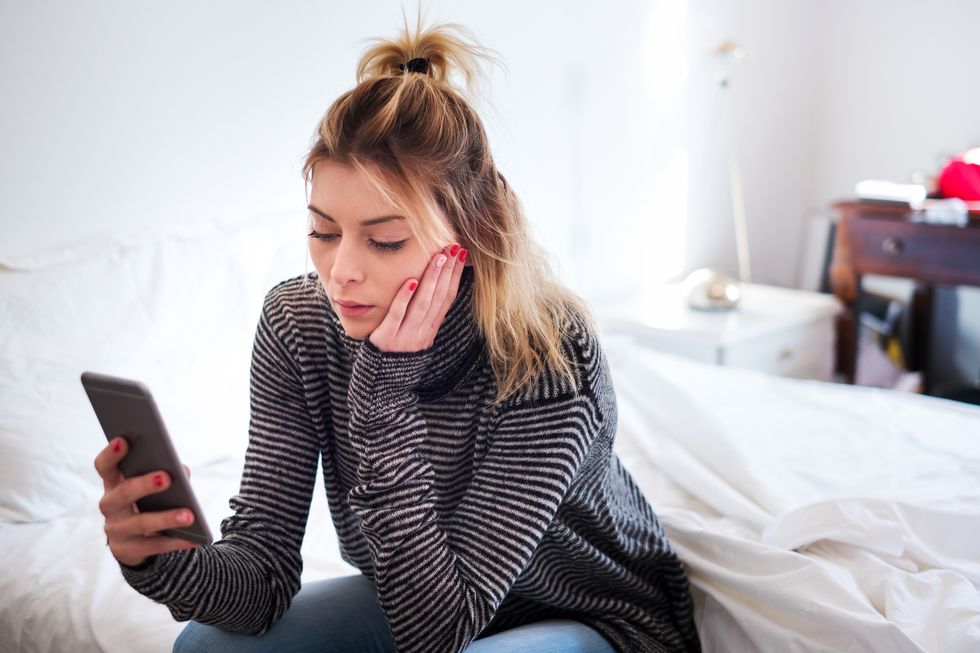 Girl holding smartphone sitting on bed