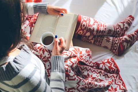 girl in bed with coffee cup reading a book
