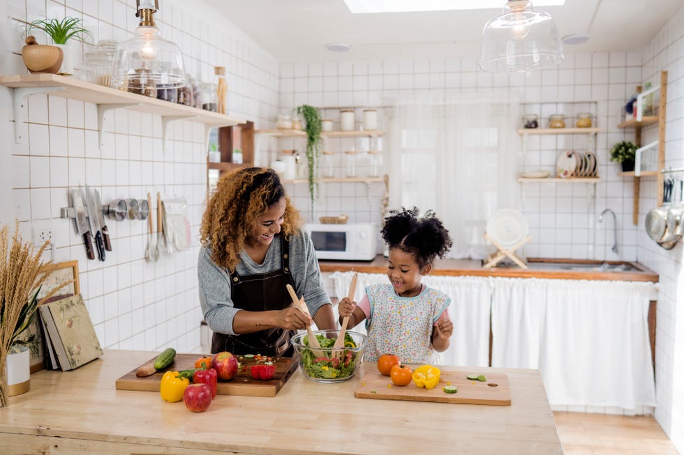 girl learning to prepare meal from mother