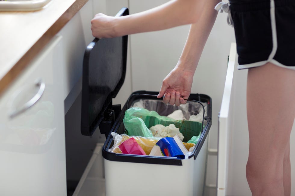 una mujer joven recicla la basura en su cocina