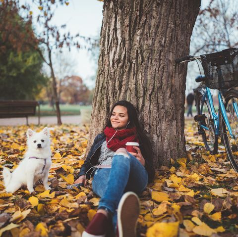 girl with her dog drinking coffee in the park