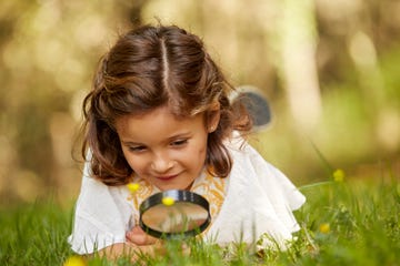 niña mirando con lupa la hierba