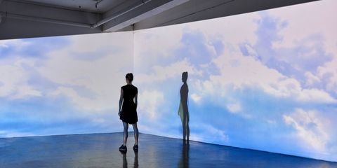 girl looking into a large scale projected image of skies