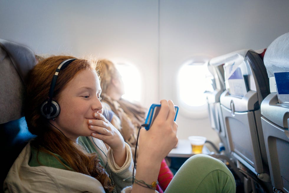 girl on an airplane watching a movie on a mobile phone