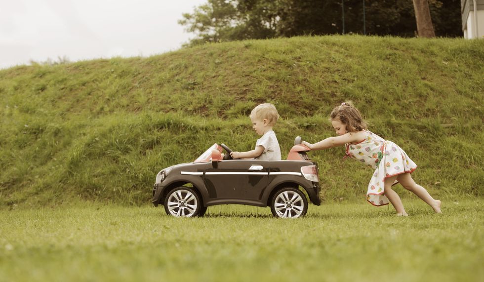 girl pushing little brother in toy car