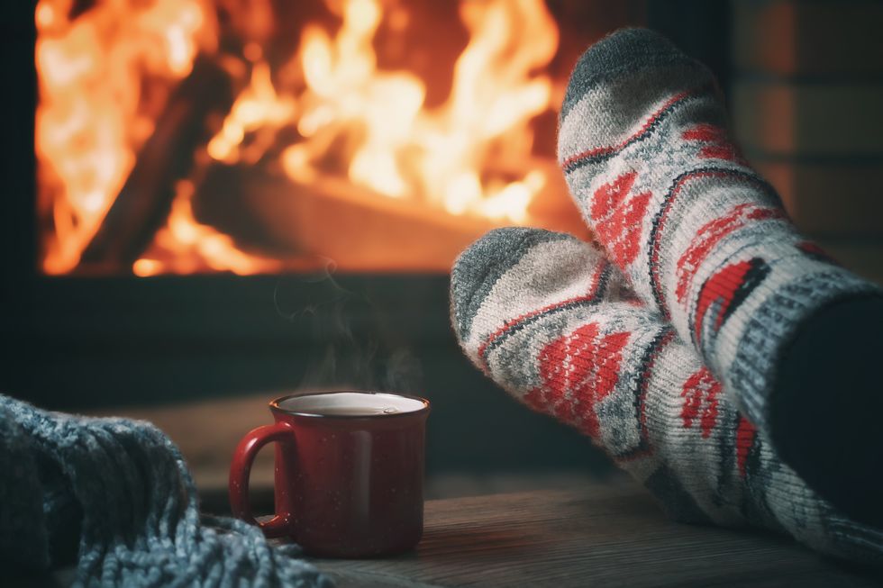 girl resting and warming her feet by a burning fireplace in a country house on a winter evening selective focus