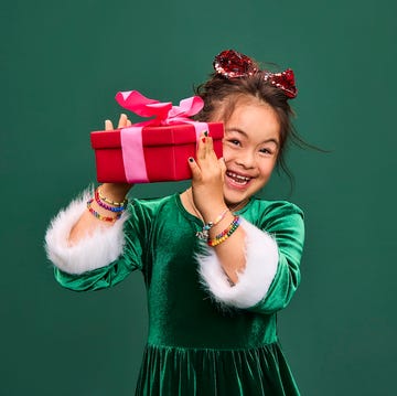girl shaking wrapped red present girl shaking wrapped red present