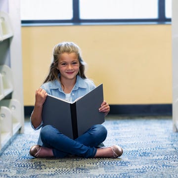 Girl sitting on floor in library, reading a book girl sitting on floor in library, reading a book