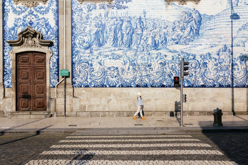 girl walking in porto, azulejos wall in background