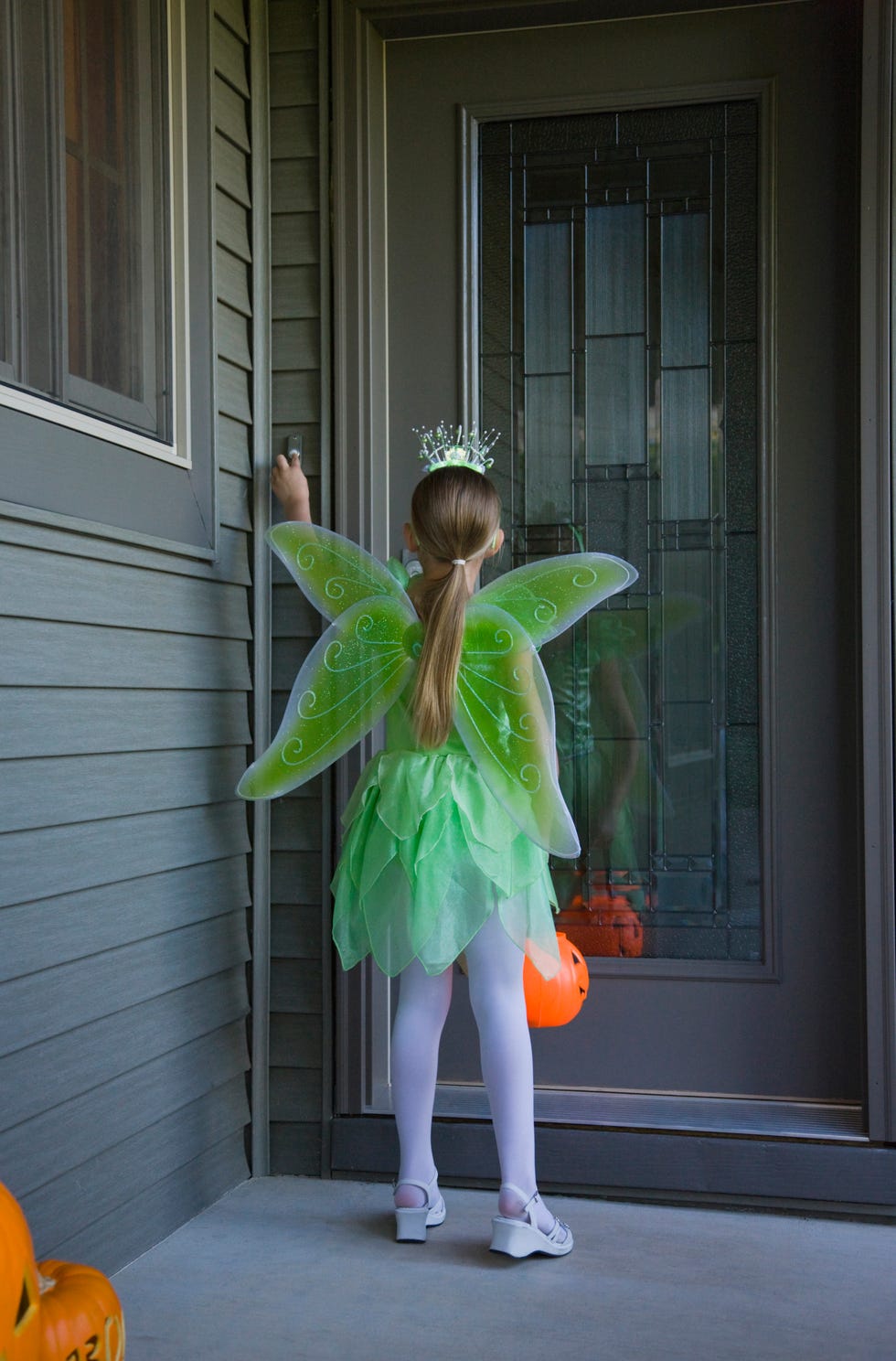 Girl (8-9) wearing fairy costume trick or treating, rear view