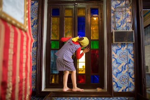 Een meisje kijkt door het gekleurde glas van een van de ruiten van de ElGhriba synagoge die rond 500 voor Christus zou zijn gebouwd