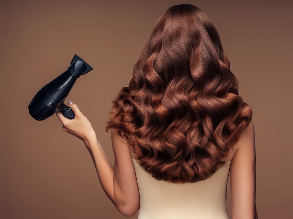 girl with a beautiful hairstyle holding a hairdryer