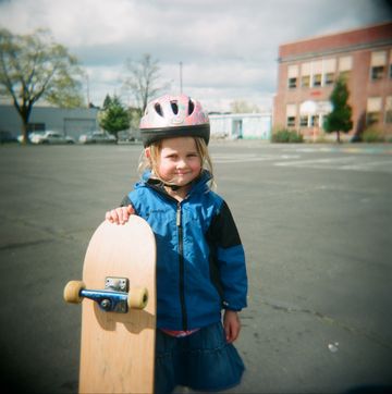 girl with bike helmet and skateboard in schoolyard