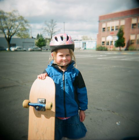 girl with bike helmet and skateboard in schoolyard