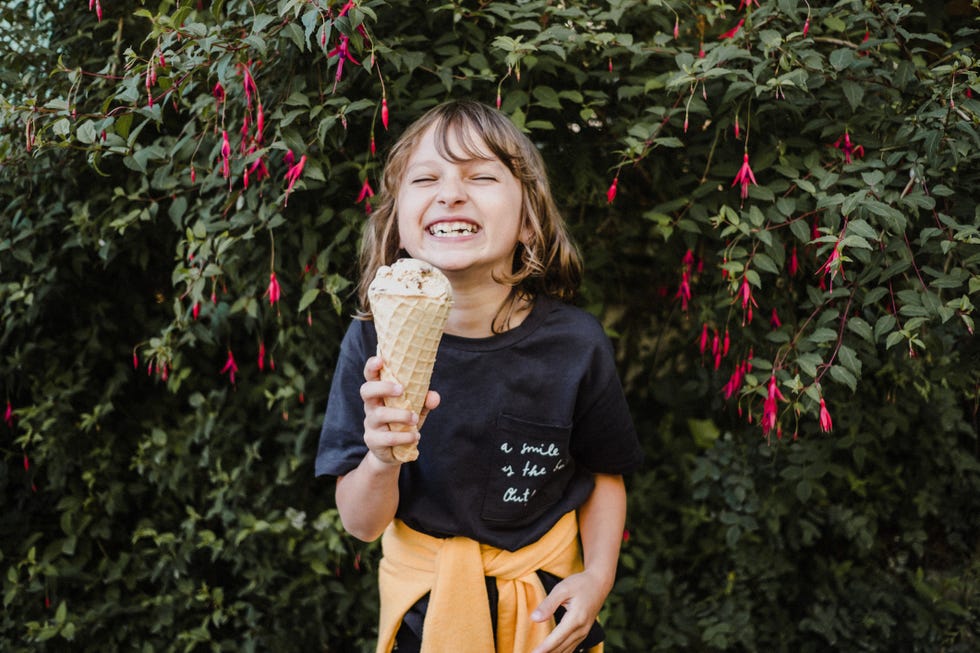 girl with ice cream cone in front of hedge