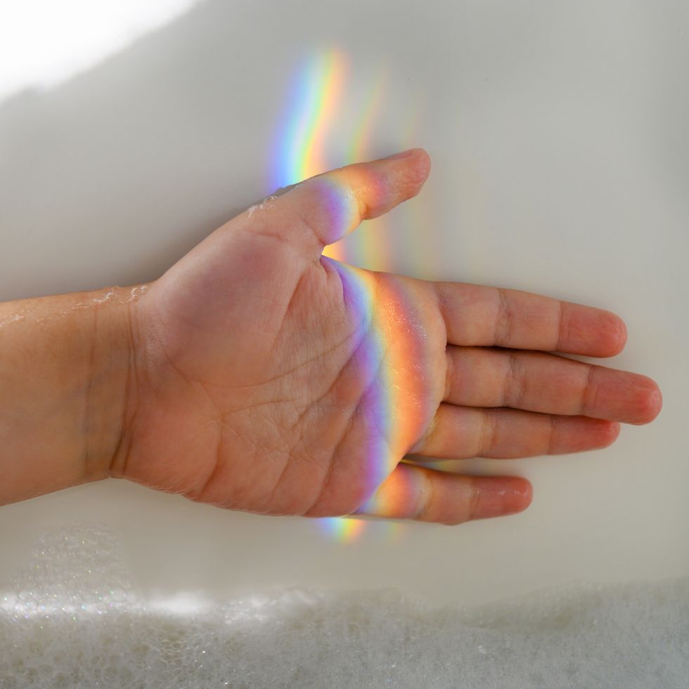 girl's hand in rainbow light beam in bubble bath