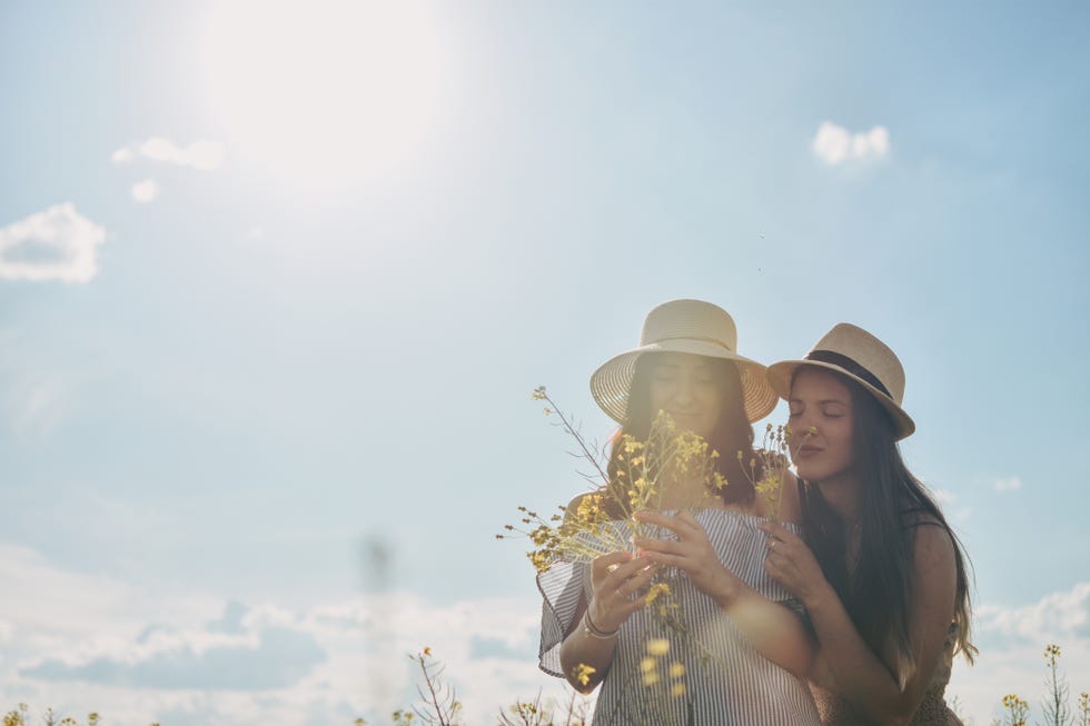 two girls holding each other and yellow flowers