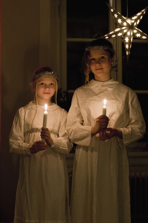 girls traditionally dressed standing with candles on st lucia's day