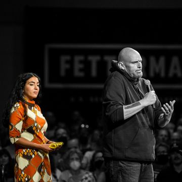 everything is black and white except for gisele fetterman who is standing behind john fetterman at a speaking event