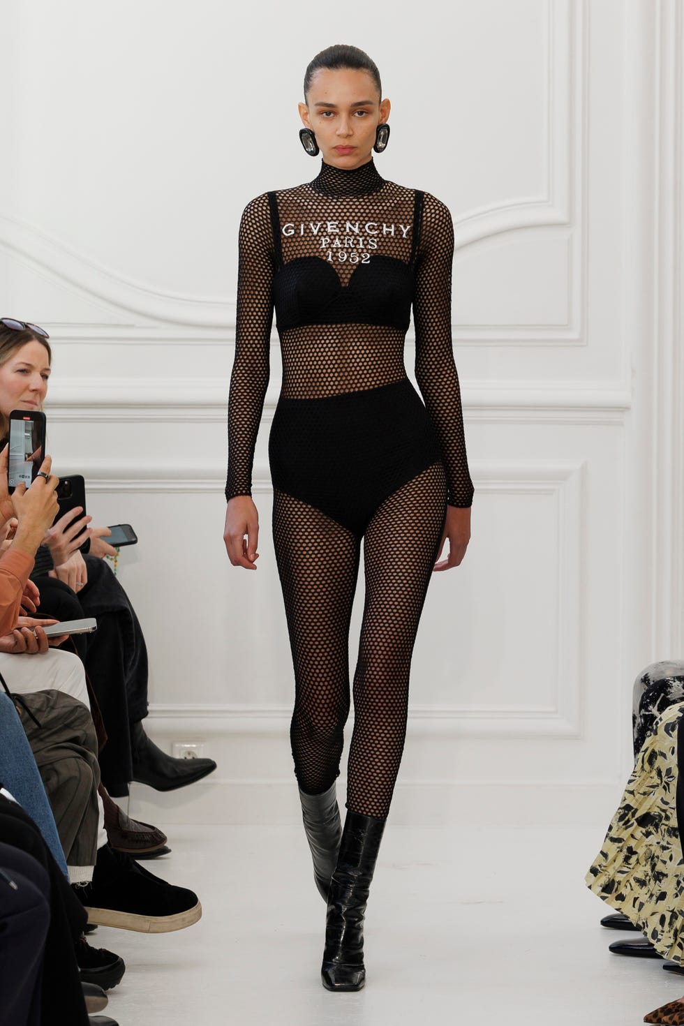 Fashion model showcasing a black mesh outfit on a runway